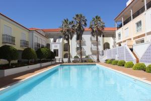a swimming pool in the courtyard of a building with palm trees at Confortavel T2 in Óbidos