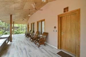 Habitación con sillas y puerta de madera. en Saj In The Forest, Pench National Park, en Seonī