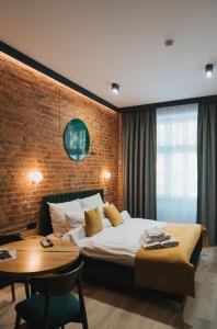 a bedroom with a bed and a table and a brick wall at Apartamenty BIBLIO in Łódź