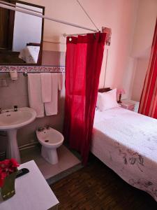 um quarto com uma cama com uma cortina vermelha e um lavatório em Pensão Prata em Lisboa