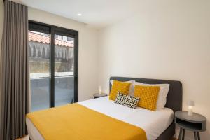 a bedroom with a bed with yellow pillows and a window at Golden City by An Island Apart in Funchal +31 photos