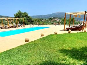 a swimming pool with chairs and a grass field at Foinikounta view in Finikounta