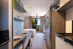 a kitchen and dining room with a table and a room with a bed at Way Bossa João Pessoa by Carpediem in João Pessoa