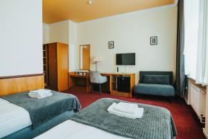 a hotel room with two beds and a desk and a chair at Polonia Raciborz in Racibórz