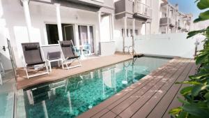 una piscina con 2 sillas junto a un edificio en Coral Compostela Beach Golf en Playa de las Americas