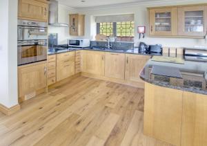 a kitchen with wooden cabinets and a wooden floor at Holly Cottage in Seaton
