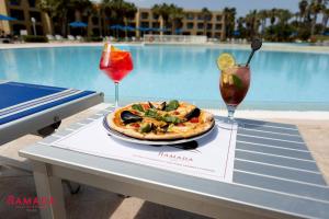 迦瑪特的住宿－Ramada Plaza by Wyndham Tunis，一张桌子,上面有比萨饼和两杯饮料