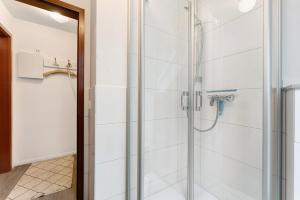 a shower with glass doors in a bathroom at Appartement Skagen in Glücksburg +10 photos
