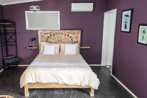 una camera con un letto con una parete viola di Byron Bay Hinterlands Dreaming Woods Cabin One a Bangalow 1 altra foto