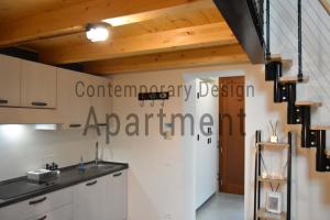 パドヴァにあるContemporary Design Loft & Apartment Padovaの白いキャビネット付きのキッチン、壁に看板