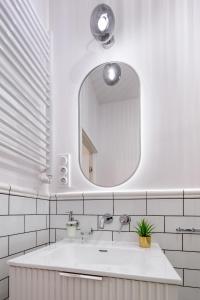 uma casa de banho branca com um lavatório e um espelho em Zjawiskowy apartament obok Dworca Głównego z Netflix i AC em Cracóvia