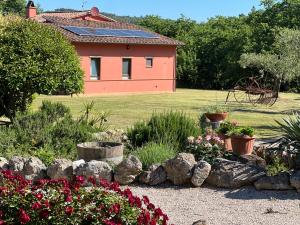 un jardín con flores y una casa de fondo en Le case di Lisetta Holiday homes en Corciano