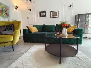 uma sala de estar com um sofá verde e uma mesa em Maximilian apartman em Smederevo
