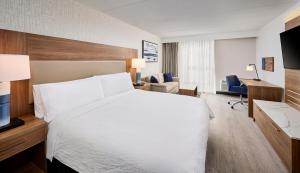 una camera d'albergo con letto bianco e scrivania di Candlewood Suites Burlington Conference Centre, an IHG Hotel a Burlington