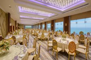 a banquet hall with white tables and chairs and windows at Araliya Beach Resort & Spa Unawatuna- Where you meet the sea all year in Unawatuna