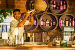 a man standing behind a bar holding up a wine glass at Araliya Beach Resort & Spa Unawatuna- Where you meet the sea all year in Unawatuna