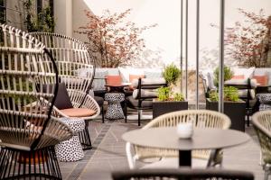 eine Terrasse mit Stühlen, Tischen und Pflanzen in der Unterkunft Motel One Karlsruhe in Karlsruhe