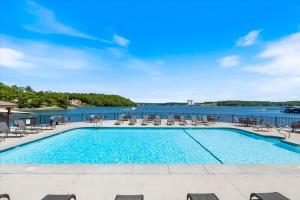 einen Pool mit Stühlen und Blick auf das Wasser in der Unterkunft Full Moon Condo in Lake Ozark