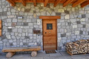 a stone building with a wooden door and a bench at Chalet Aquila - Chalet Maso Vecchio fra le montagne del Trentino in Castello Tesino