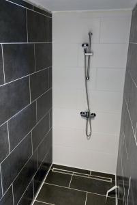a bathroom with a shower with black tiles at Anker in Waabs