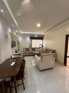 sala de estar con sofá, mesa y sillas en Danat Layalina Apparthotel, en Al Namas