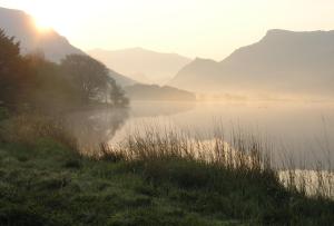 een mistig meer met bergen op de achtergrond bij Trigonos - Peaceful Lakeside Vegetarian B&B and Retreat in Eryri National Park in Caernarfon +91 foto's