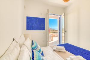 a white room with a bed and a door to a balcony at Paros Sea View Eco - Aetherian Ciel Villas, Alia in Mármara