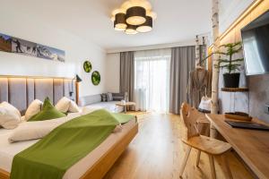 a bedroom with a large bed with a green blanket at Hotel Lärchenhof in Katschberghöhe