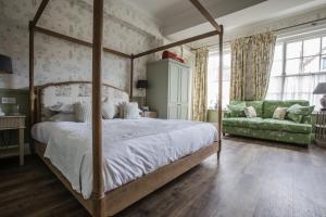 1 dormitorio con cama con dosel y sofá verde en The George Hotel and Beach Club en Yarmouth