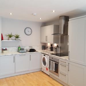een keuken met witte kasten en een wasmachine bij A Superb One Bed Apt In The Heart Of The City in Nottingham