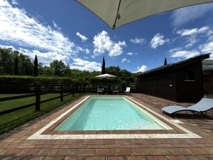 a swimming pool with a patio and an umbrella at Agriturismo LeGi Toscana in Pietraviva