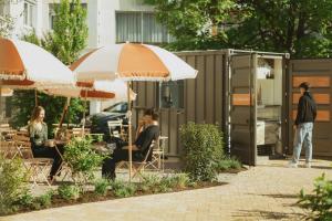 Un groupe de personnes assises à des tables sous des parasols dans l'établissement 2Places Soul, à Lörrach