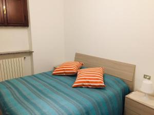 a bed with two orange and blue pillows on it at Domus KA 2 in Cremona