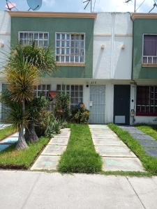 un bâtiment vert et blanc avec des palmiers devant lui dans l'établissement Llegaste a casa almendros, à Santa Cruz Tecamac