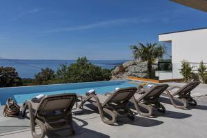 a group of chairs sitting next to a swimming pool at Villa Marta - Luxury Villa! - Makarska Exklusiv in Baška Voda