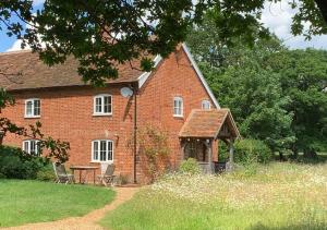 een rood bakstenen huis met een prieel ervoor bij Boot Cottage in Sudbourne
