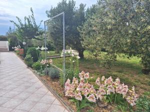 a garden with pink flowers next to a sidewalk at Apartments Donadic I, Caska in Novalja