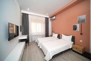 a hotel room with two beds and a desk at Sweet Home Apart-Hotel in Yerevan