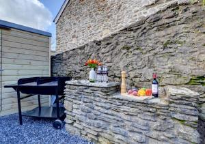 uma parede de pedra com uma mesa e garrafas de vinho em Lower Dean Farm em Trentishoe