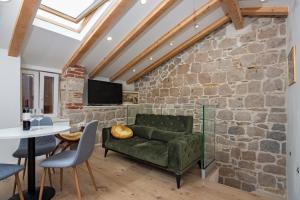 ein Wohnzimmer mit einer grünen Couch und einer Steinmauer in der Unterkunft Maki Stone House - Parking on request ! in Split