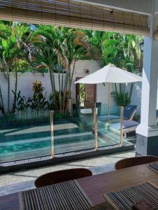 a swimming pool with a table and an umbrella at Glisten Up Villa Beach Side Sanur! in Sanur