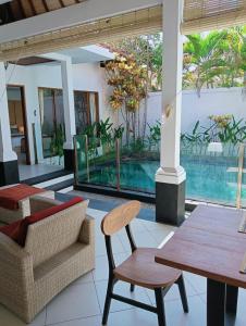 a patio with a table and chairs and a pool at Glisten Up Villa Beach Side Sanur! in Sanur +21 photos