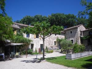 a stone house with a tree in front of it at Les Esplanes in La Garde-Adhémar