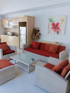 a living room with a red couch and a table at Glisten Up Villa Beach Side Sanur! in Sanur