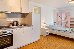 a kitchen with white cabinets and a bed in a room at In der Stadt und Natur in Calw