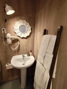 a bathroom with a sink and a mirror and towels at Stressfree Apartamento in Vila Nova de Milfontes