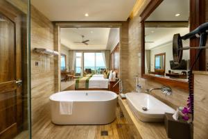 a bathroom with a tub and a large mirror at Araliya Beach Resort & Spa Unawatuna- Where you meet the sea all year in Unawatuna