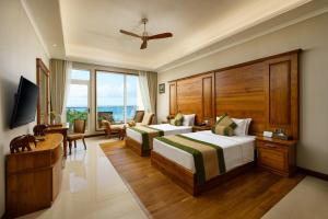 a hotel room with two beds and a desk at Araliya Beach Resort & Spa Unawatuna- Where you meet the sea all year in Unawatuna