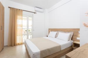 a white bedroom with a bed and a balcony at Iasmos - Yiasemi in Pefkohori