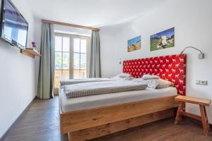 - une chambre avec un grand lit et une tête de lit rouge dans l'établissement Feriennest Leitner, à Maria Alm